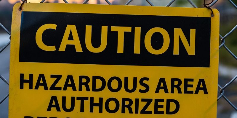 Caution sign for hazardous area on metal fence